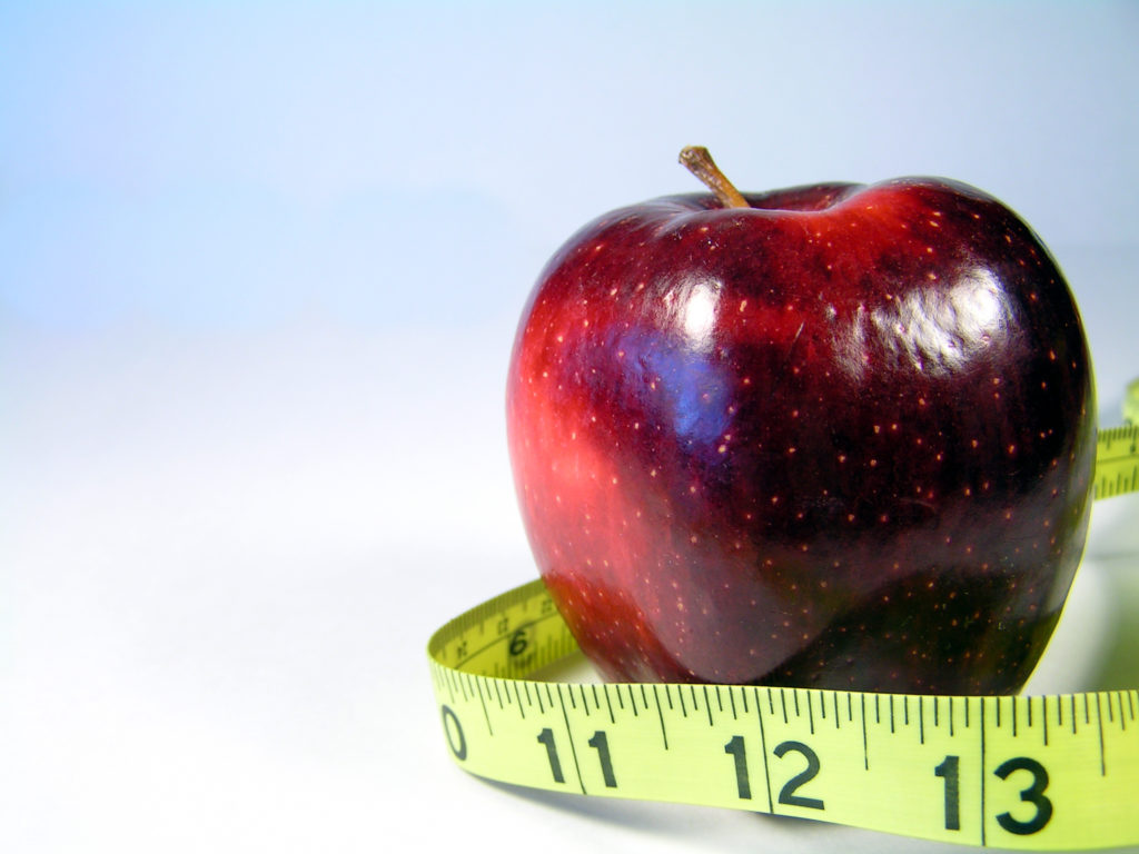 apple on white with measuring tape signifying weight watching or weight loss
